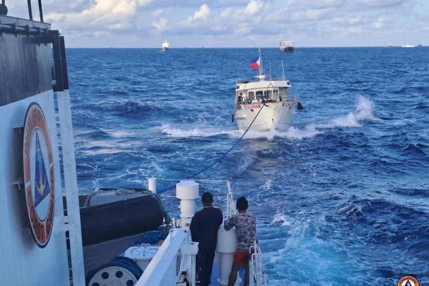 photo taken on board a larger ship, which is towing a smaller ship seen flying the Philippines flag