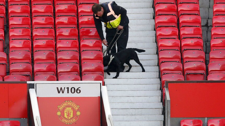 A police sniffer dog and its handler moves through the stands at Old Trafford.