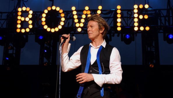 David Bowie performs in 2002 in front of his name illuminated in lights