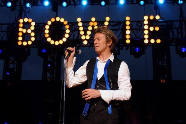 David Bowie performs in 2002 in front of his name illuminated in lights