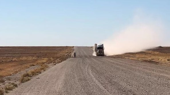 A big truck throws up dust as it passes Phil McDonald on the Eyre Development Road on the way to Bedourie.