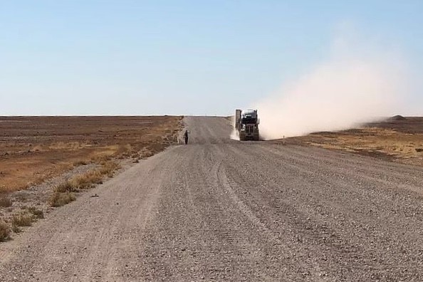 A big truck throws up dust as it passes Phil McDonald on the Eyre Development Road on the way to Bedourie.