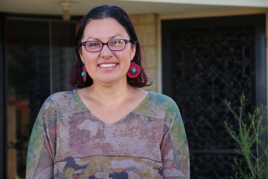 Woman stands in front of house, smiling