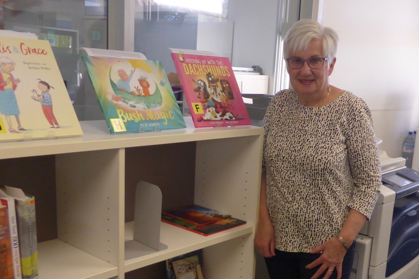 Woman standing in library near children's books on shelves