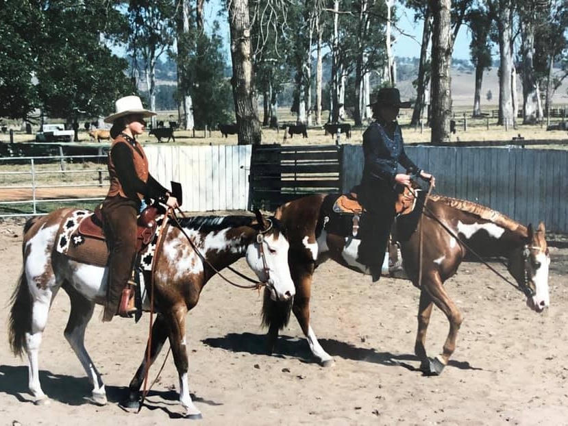 Two multi coloured horses stand next to each other, one ridden by Lana, the other her mother. 