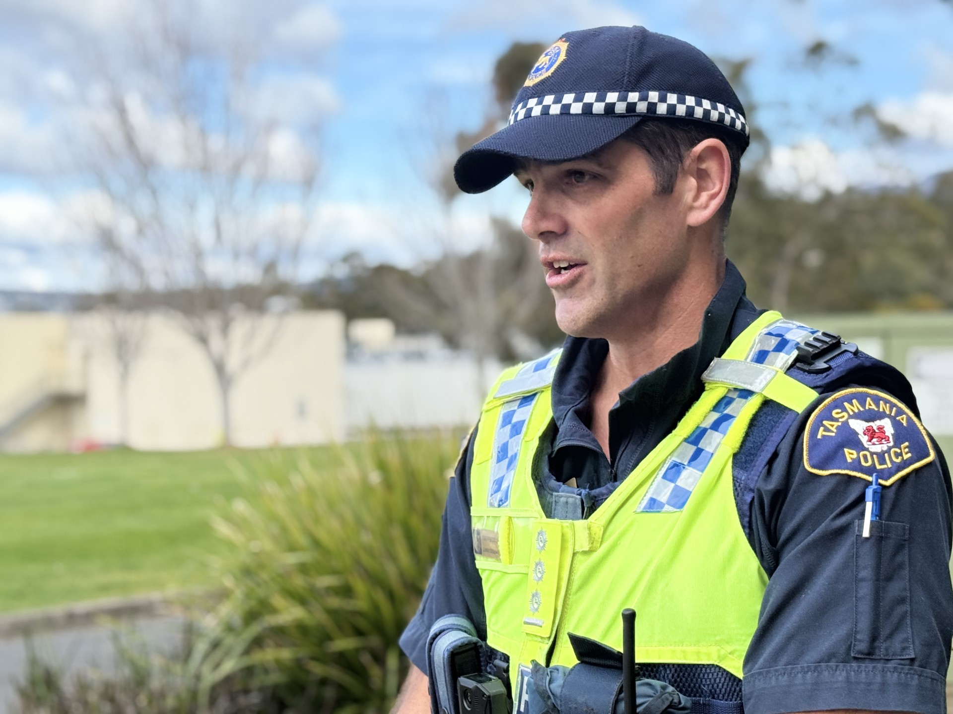 A police officer in a yellow vest and blue hat shown in profile