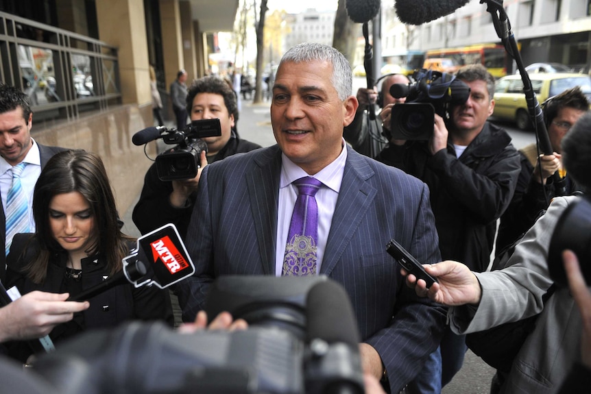 Gangland figure Mick Gatto leaves the Melbourne Magistrates Court, surrounded by media.