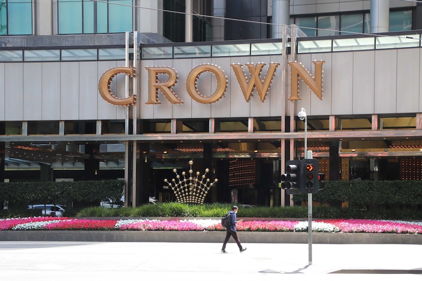 A man walks past a bed of flowers outside the entrance to Crown Casino.