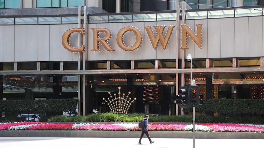A man walks past a bed of flowers outside the entrance to Crown Casino.
