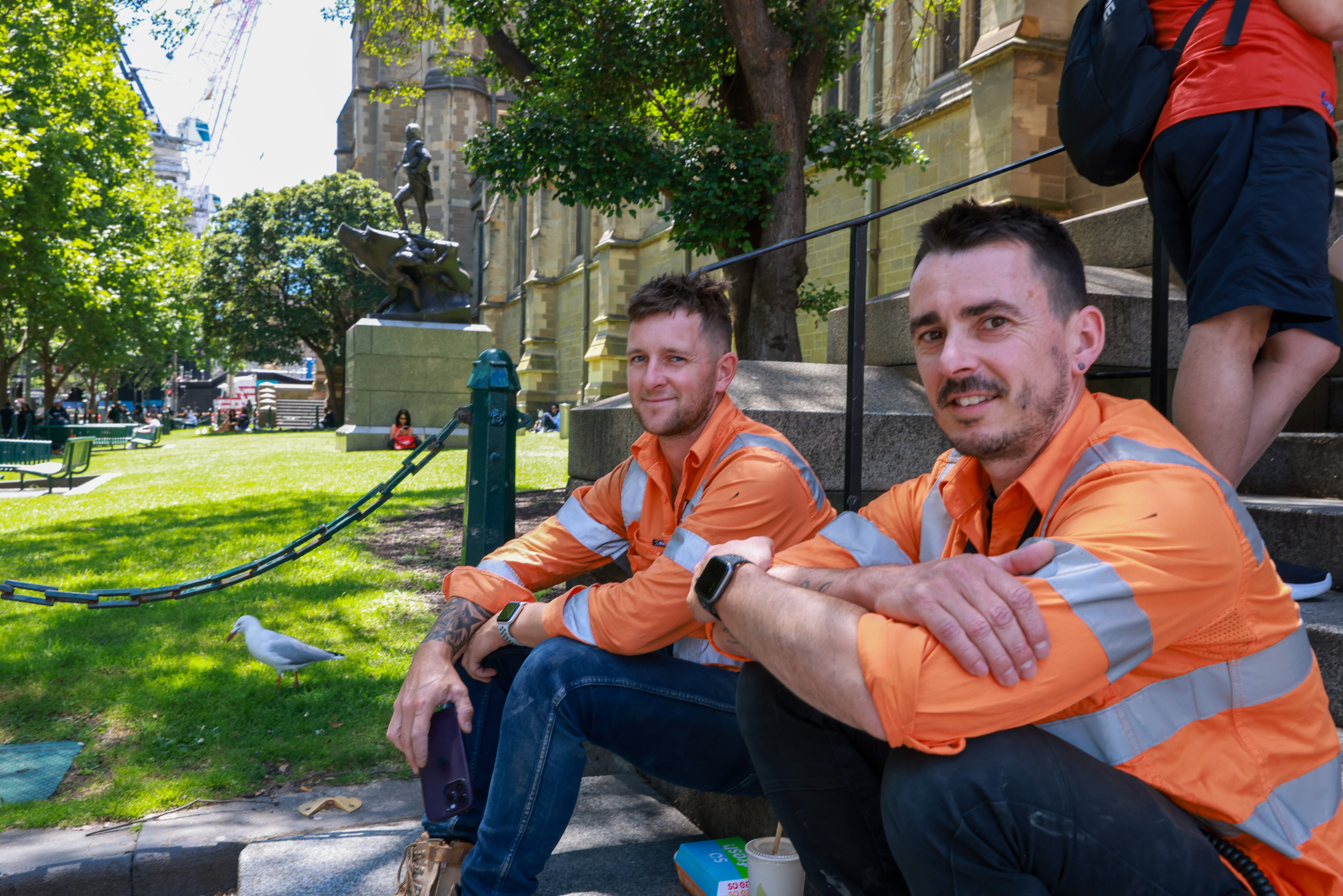 Faded social distance stickers on the footpath and people walking with masks as they pass hand sanitiser stations.