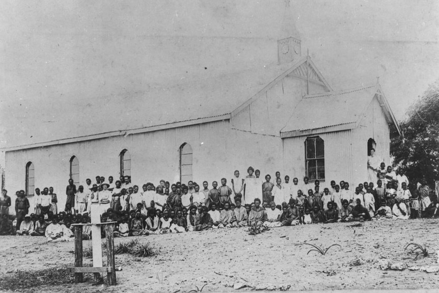 Historic black and white picture of large group of Aboriginal people gathered outside old church