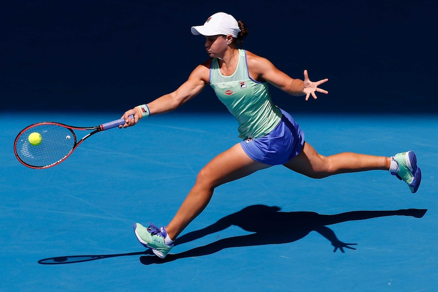 Ash Barty acrobatically stretches full-length to reach a forehand.