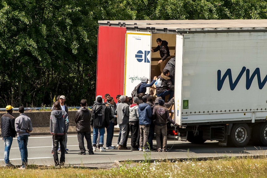 Migrants climb in the back of a lorry on the A16 highway leading to the Eurotunnel on June 23, 2015 in Calais, northern France
