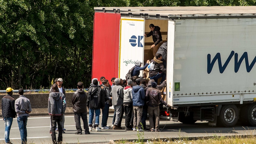 Migrants climb in the back of a lorry on the A16 highway leading to the Eurotunnel on June 23, 2015 in Calais, northern France