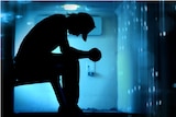 Silhouetted anonymous youth sits on bench in a detention centre.