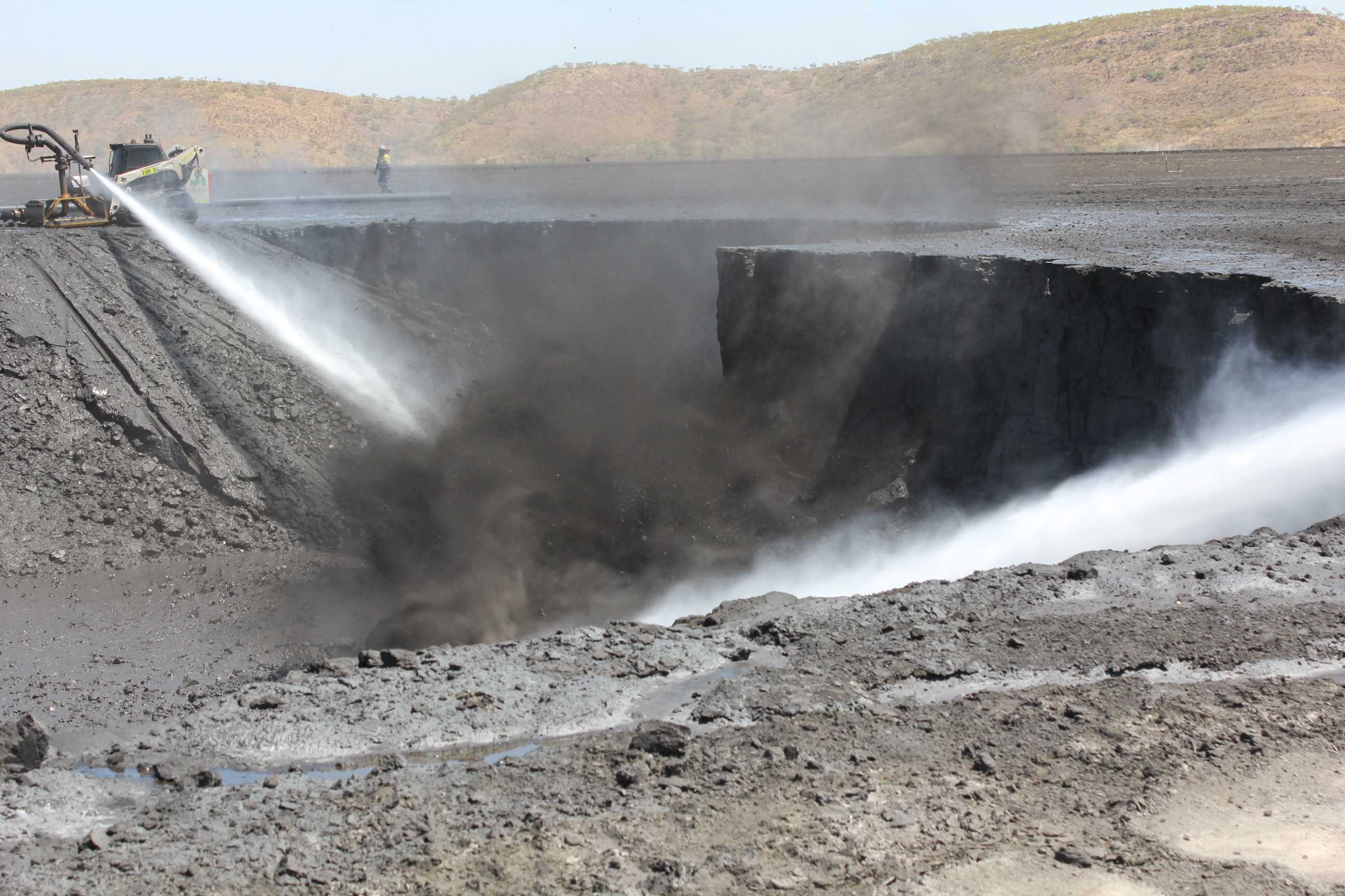 High pressure hoses blasting through the surface of a dried up dam