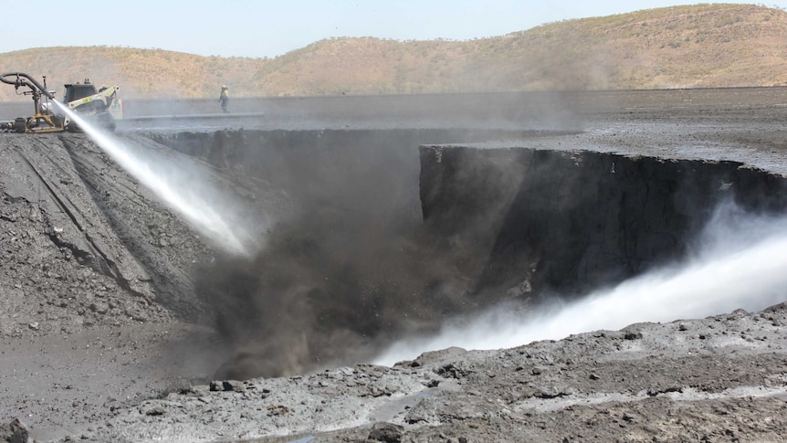 High pressure hoses blasting through the surface of a dried up dam