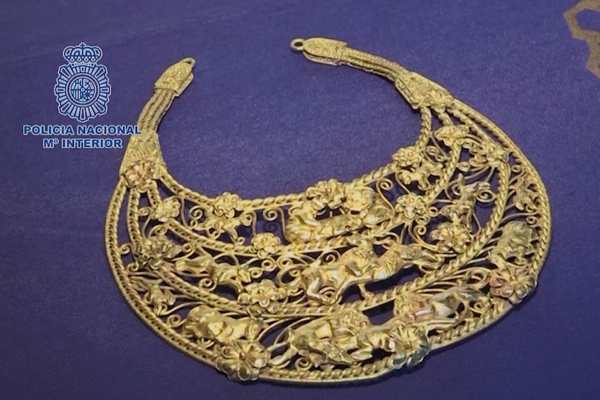 A gold necklace lays on purple velvet 