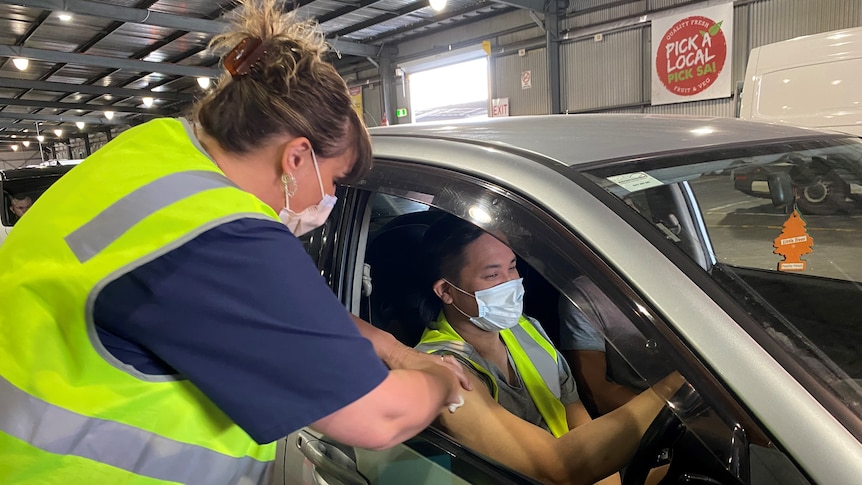 A nurse leans into the window of a car to test the driver