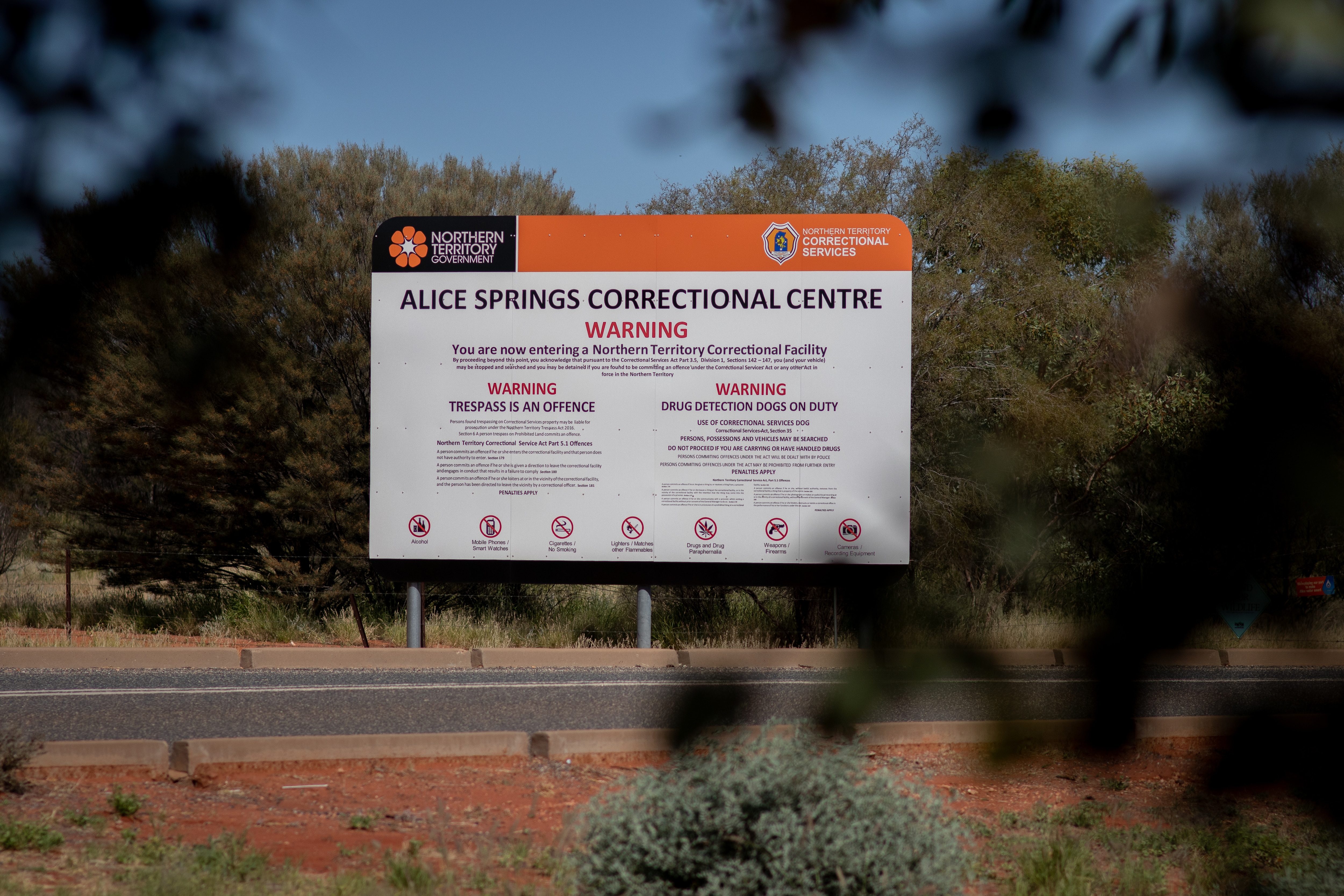 Uma placa em uma paisagem do outback diz: Centro Correcional de Alice Springs