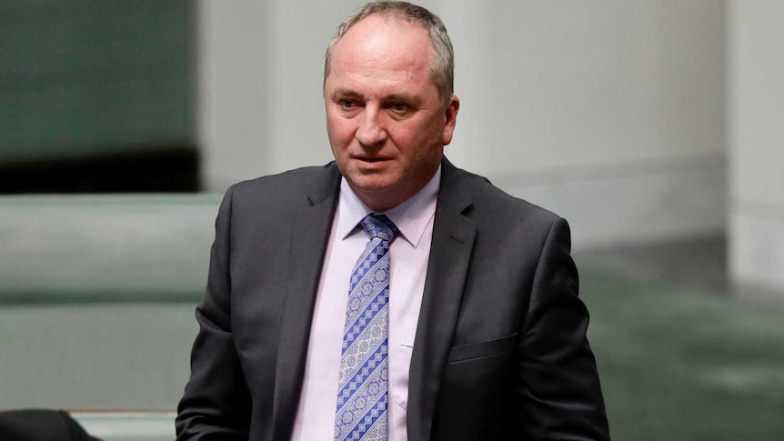 A man stands up in Australian parliament, he is balding and standing in the aisle.