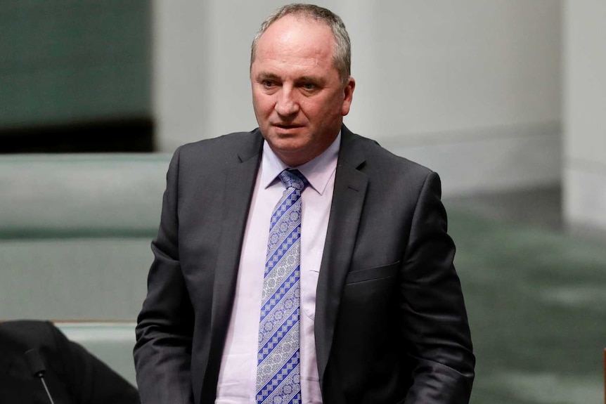 A man stands up in Australian parliament, he is balding and standing in the aisle.