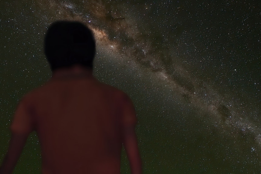 A young boy is looking out at the night sky