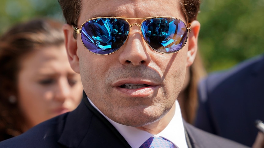 A close up of a man in a suit wearing sunglasses