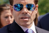 A close up of a man in a suit wearing sunglasses
