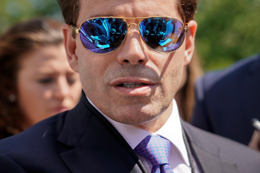 A close up of a man in a suit wearing sunglasses