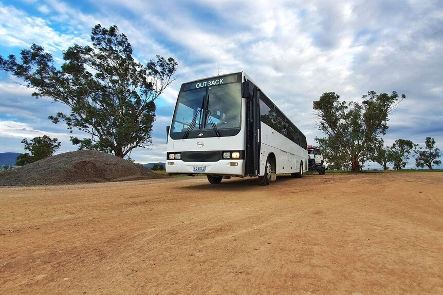 A modified white bus, towing a four-wheel-drive vehicle behind it, parked at a property near Charleville in outback Queensland.