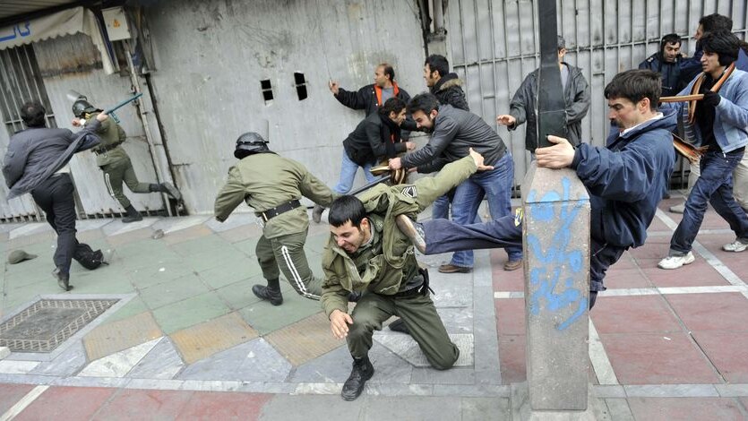 Iranian opposition supporters beat police forces during clashes in central Tehran