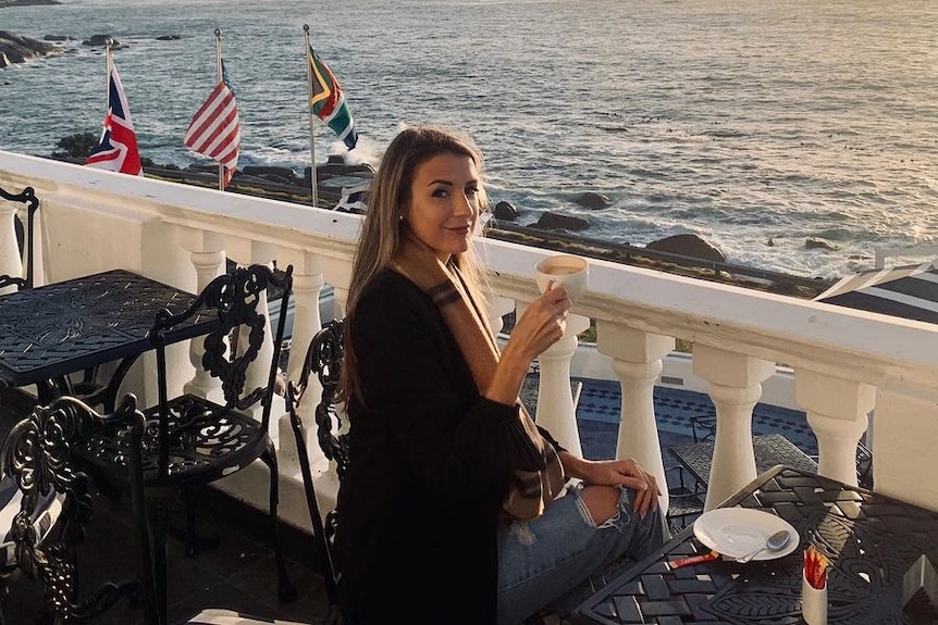 a woman drinking a coffee by a sunset in Cape Town