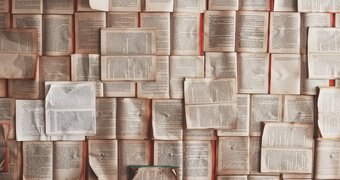 Many books are open in front of a red background, some vertical, some horizontal.