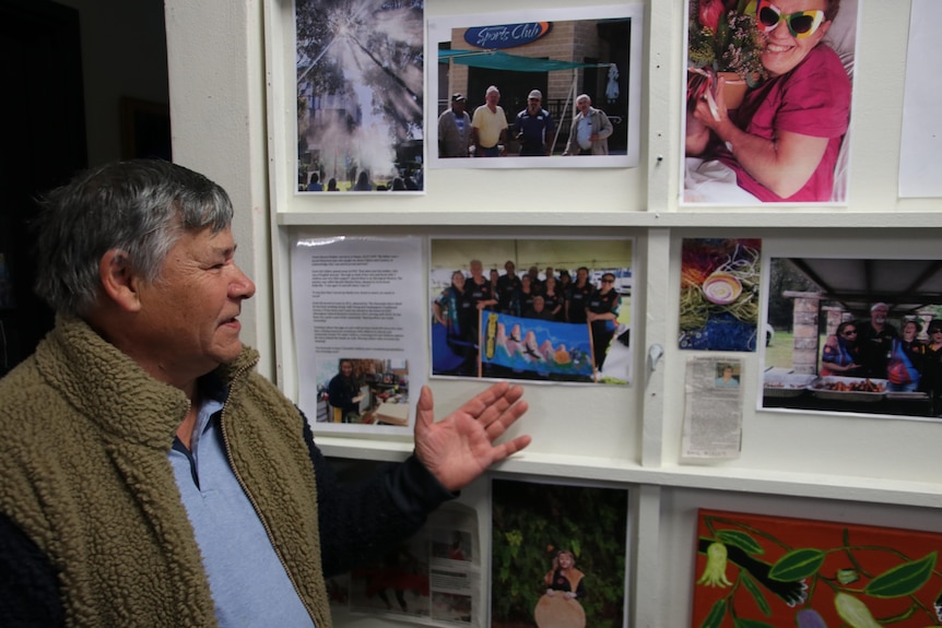 an elderly man pointing to a picture