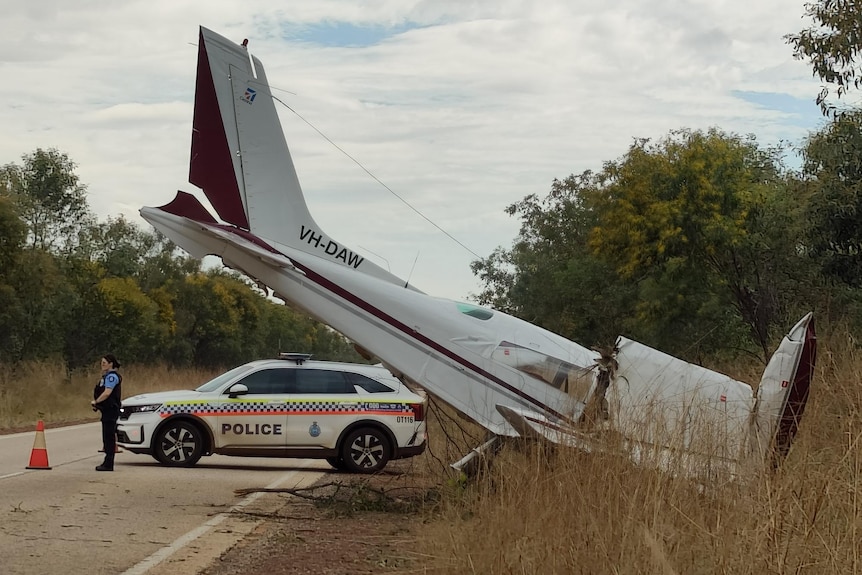 A plane crashed on the side of a road, with a police car in attendance