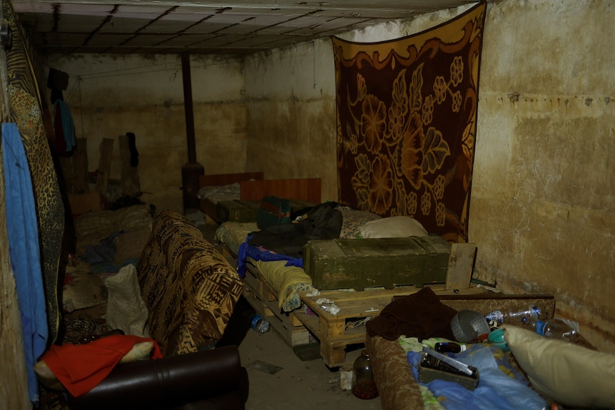 A small room cramped with beds, couches and artillery. 