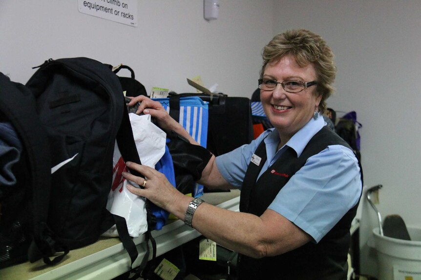 Denise Brotherton inspecting bags and smiling for the camera,