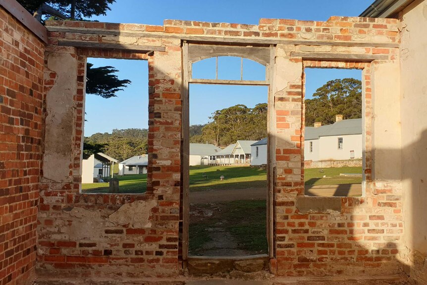 An old brick building looking towards a convict settlement with a wombat and geese in the distance.