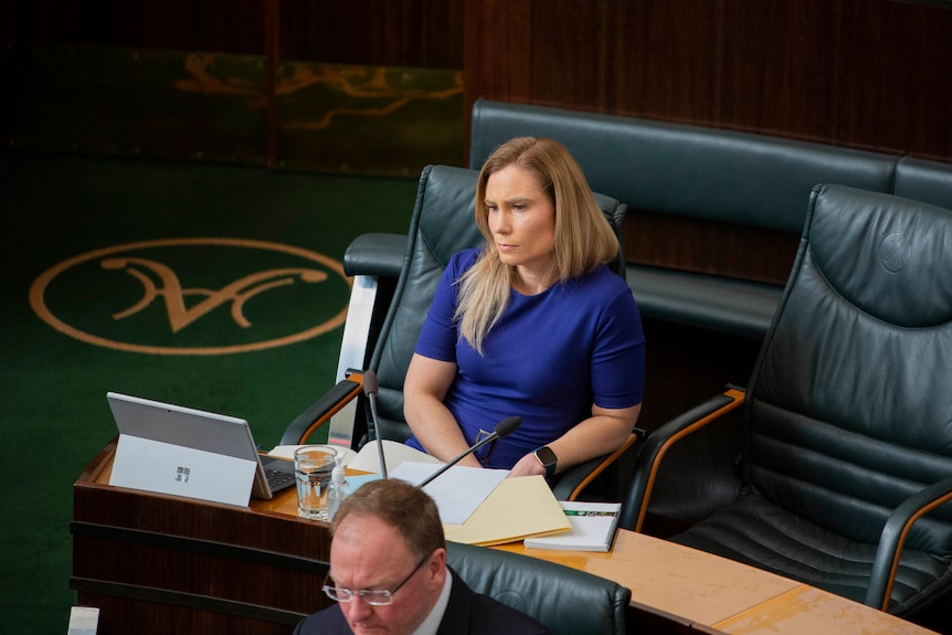 A woman sits in a chair listening intently.