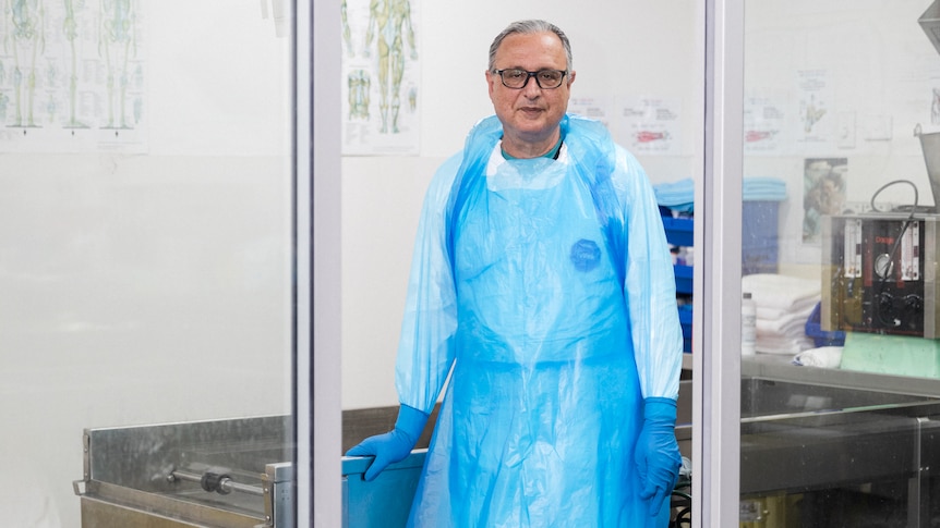 An embalmer at a morgue in protective equipment