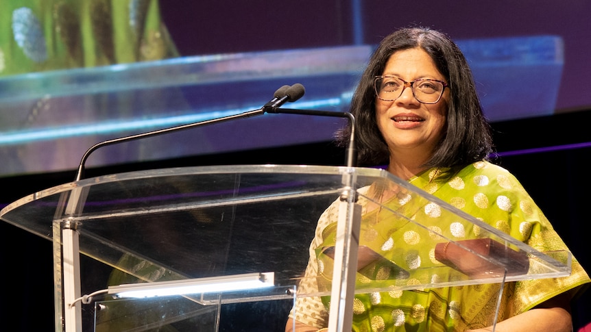 Indian school teacher in traditional dress with glasses accepts award on stage