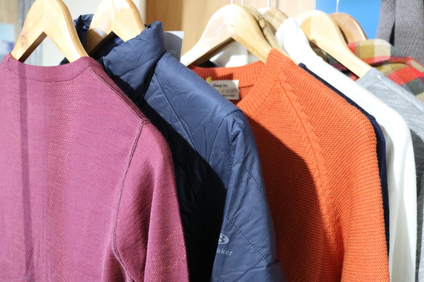different coloured merino jumpers and jackets hanging on a rack