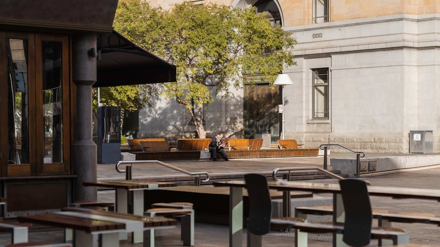 A lone pedestrian sits on a bench at a deserted public meeting space in Perth's CBD.