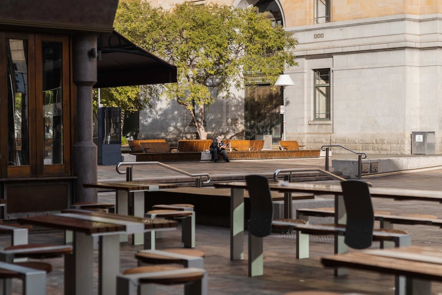 A lone pedestrian sits on a bench at a deserted public meeting space in Perth's CBD.