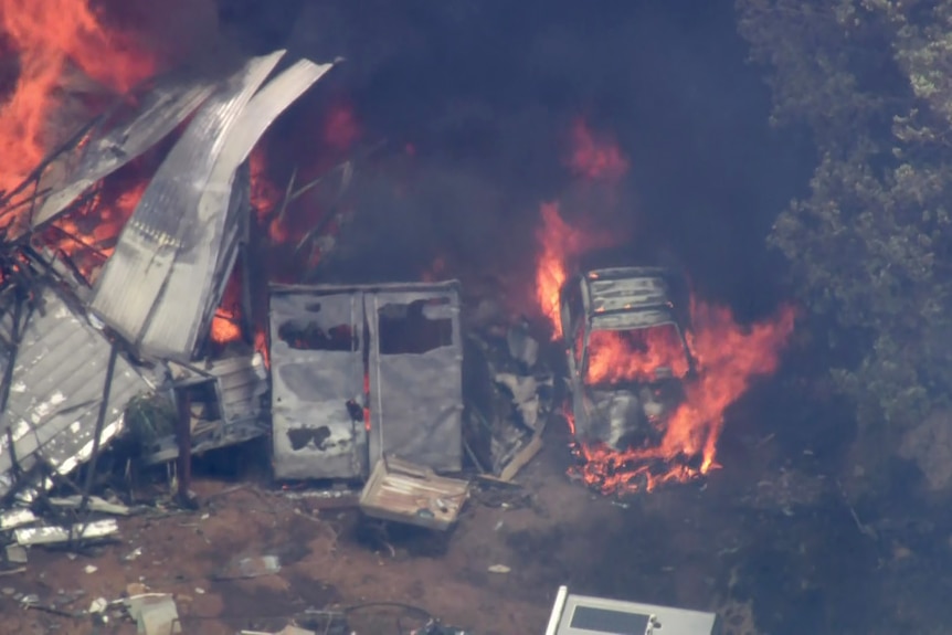 An aerial image of a car and nearby property on fire during a bushfire in a semi-rural area of Perth.