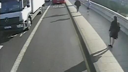 A still from CCTV footage showing a woman walking across a bridge with a jogger running towards her.