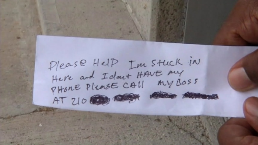 A handwritten note passed to ATM customers by a trapped worker, asking for help.