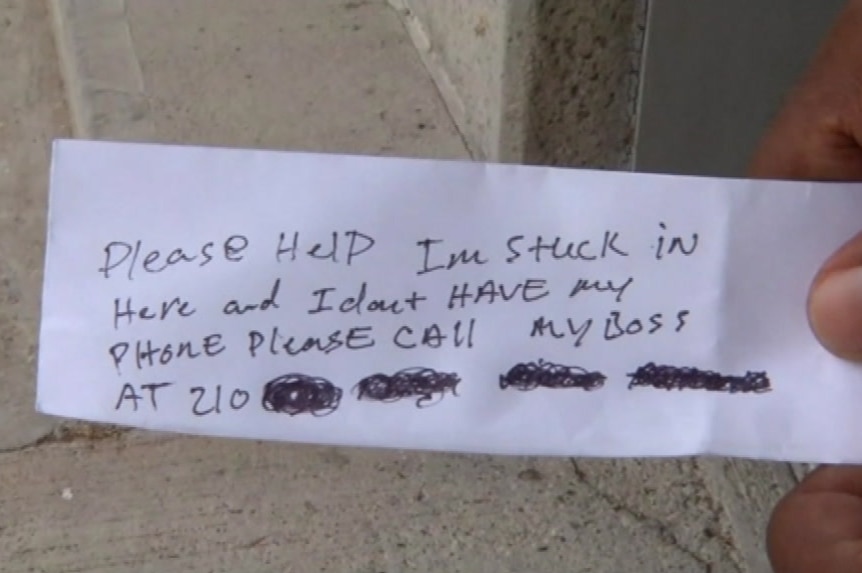 A handwritten note passed to ATM customers by a trapped worker, asking for help.
