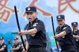 Chinese special force police officers perform a striking motion with a baton at a security oath-taking rally.